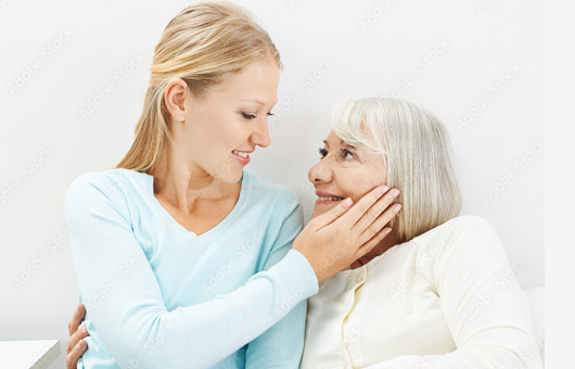 caregiver and elderly woman smiling to each other